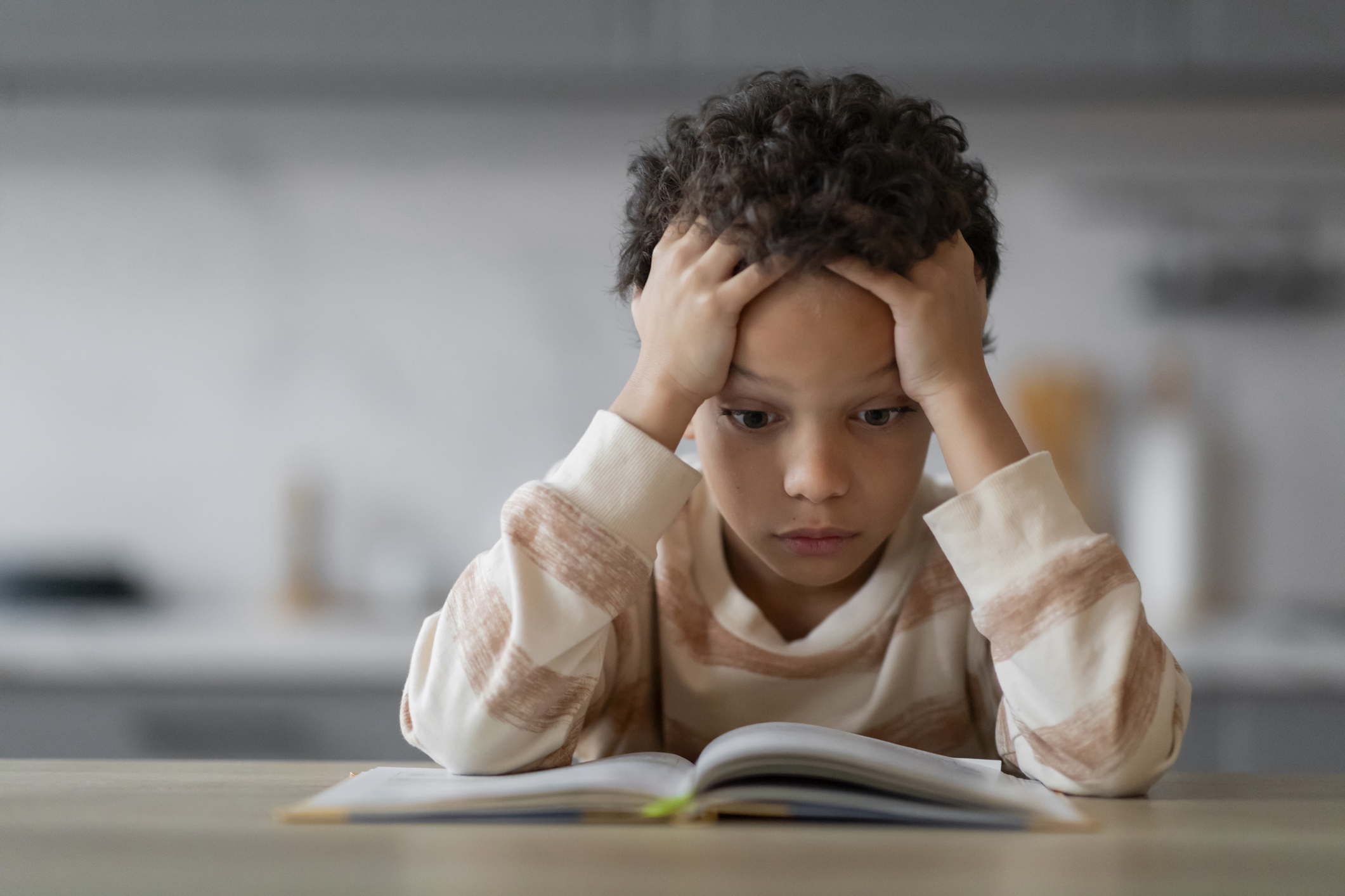 Stressed Little Black Boy Reading Book At Home And Touching Head stock photo